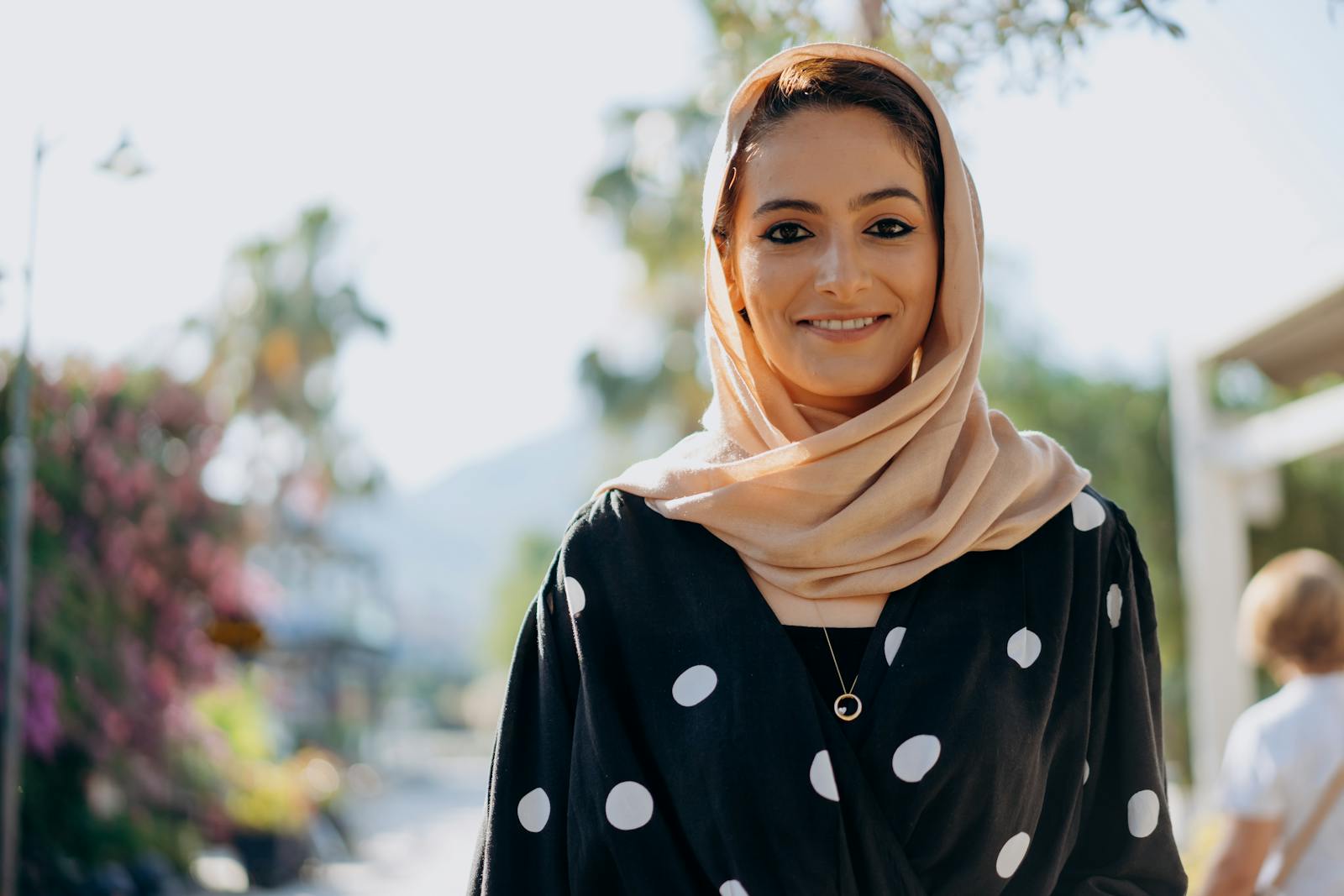 Portrait of a smiling woman in a hijab posing outdoors on a sunny day